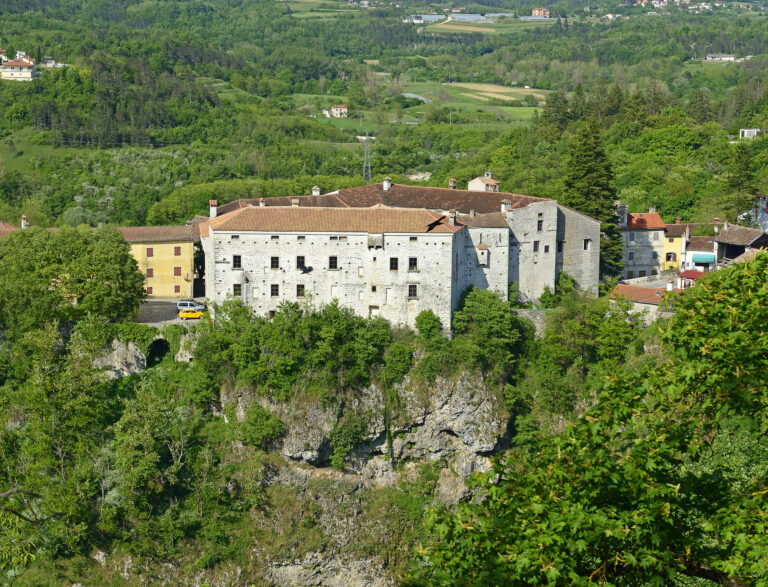 Pazin Castle stands above a rocky ravine, surrounded by trees and the green hills of inland Istria.