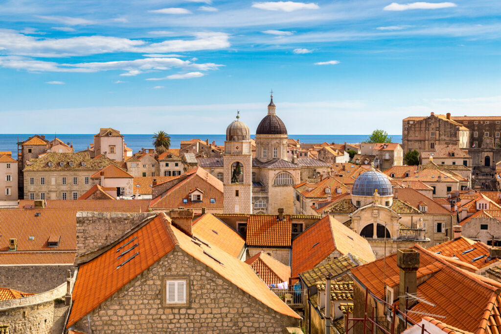 Red-tiled rooftops and historic domes fill Dubrovnik Old Town, with the Adriatic Sea beyond.