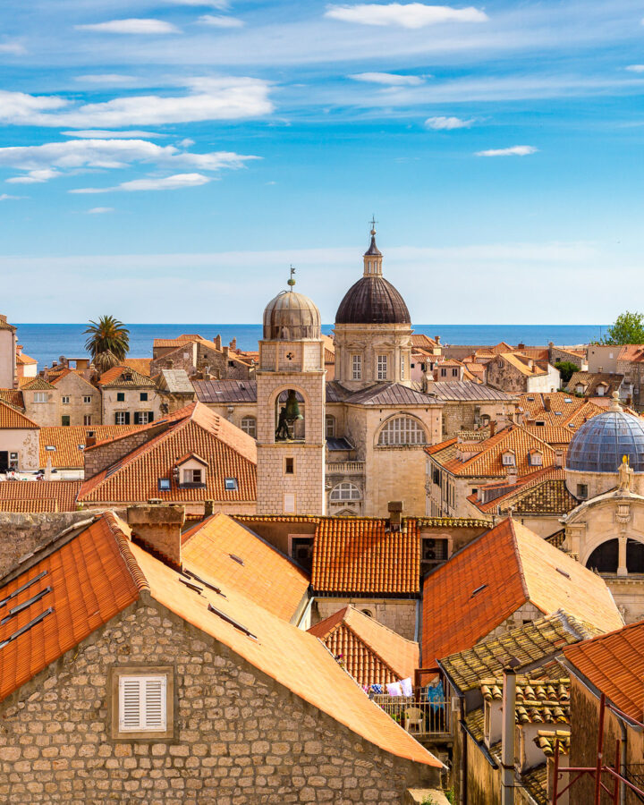 Red-tiled rooftops and historic domes fill Dubrovnik Old Town, with the Adriatic Sea beyond.