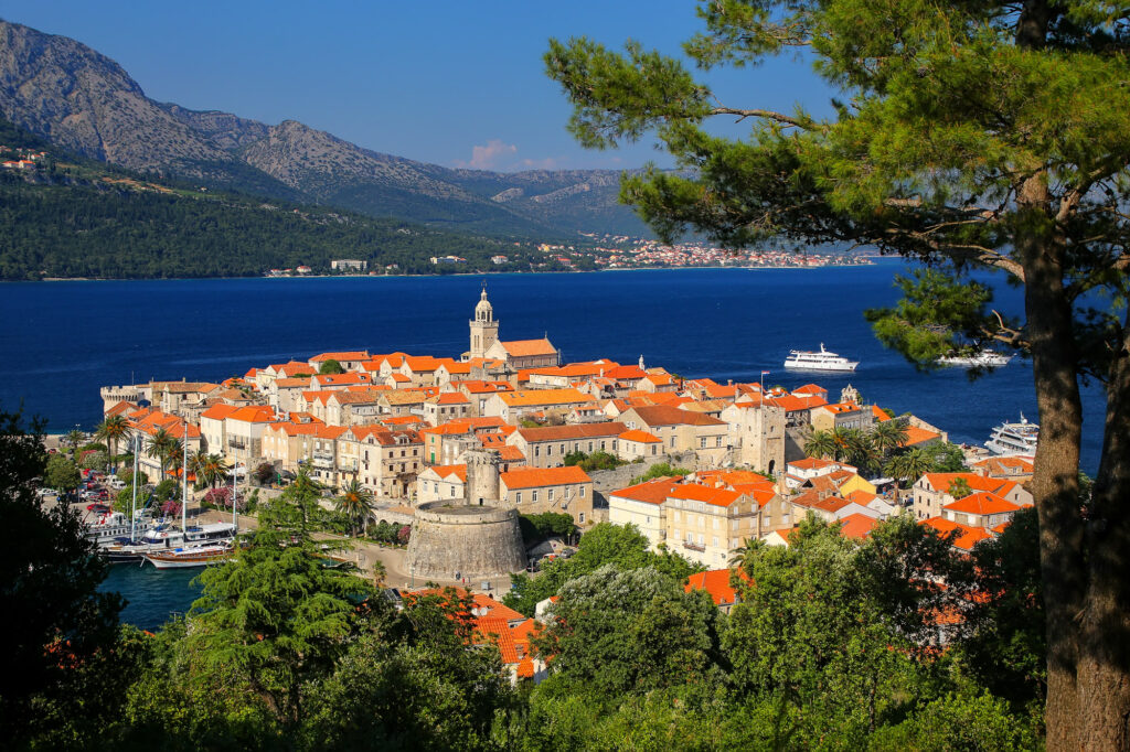 Korčula Town’s red-roofed old town beside the blue channel, framed by pine trees