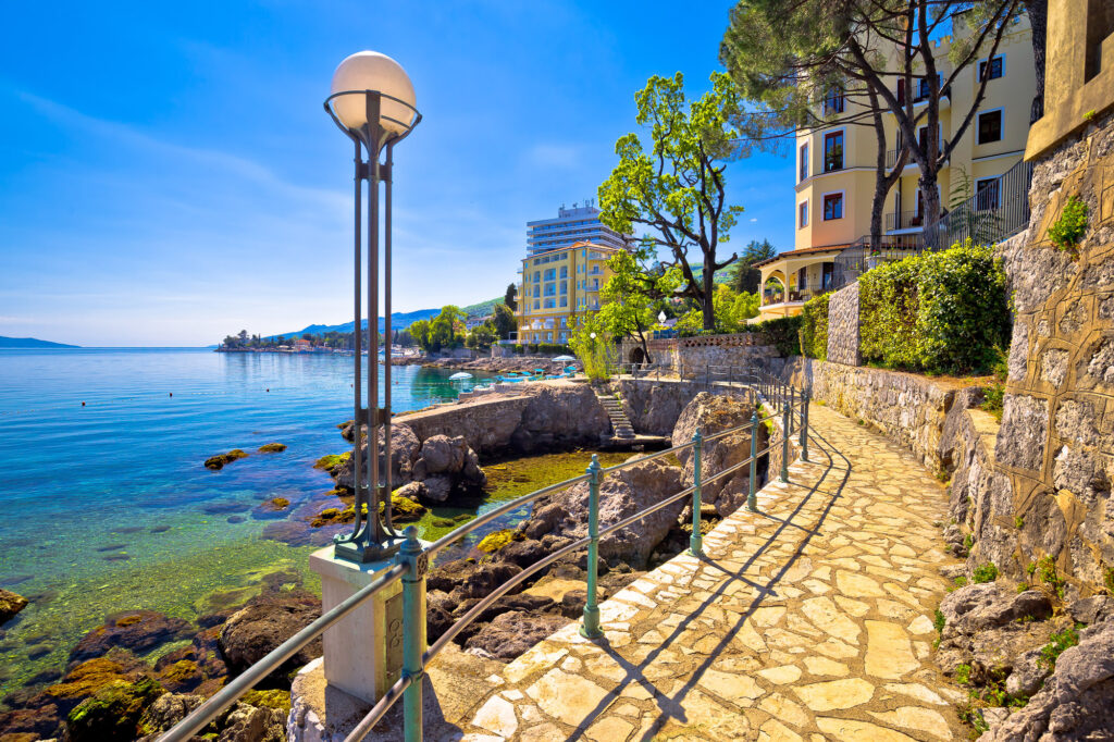 Stone promenade beside the rocky shoreline and clear blue sea in Opatija