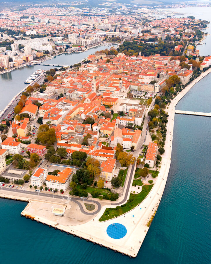Aerial view of Zadar Old Town on its peninsula, with red-roofed buildings, harbour and Adriatic Sea.