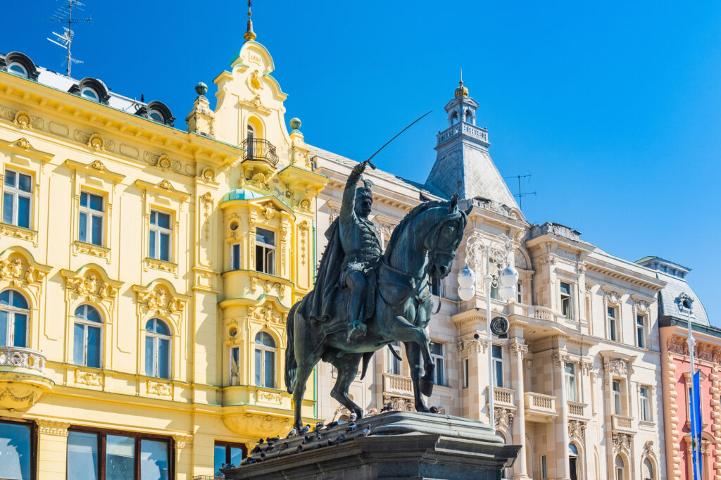 Equestrian statue of Ban Josip Jelačić in Zagreb's main square, framed by ornate historic buildings.