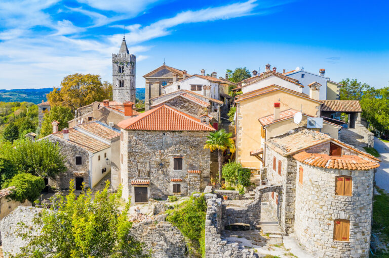 Stone houses with terracotta roofs and a church tower in Hum, Istria.