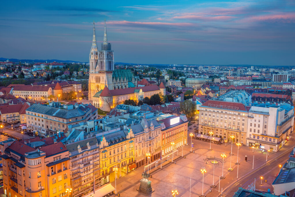 Zagreb Cathedral rises above the city centre as streetlights glow at dusk.