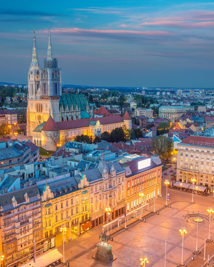 Zagreb Cathedral rises above the city centre as streetlights glow at dusk.
