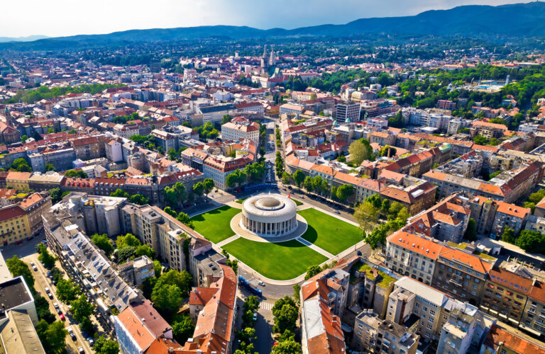 Aerial view of Zagreb, with the circular Meštrović Pavilion in the foreground and hills beyond the city.