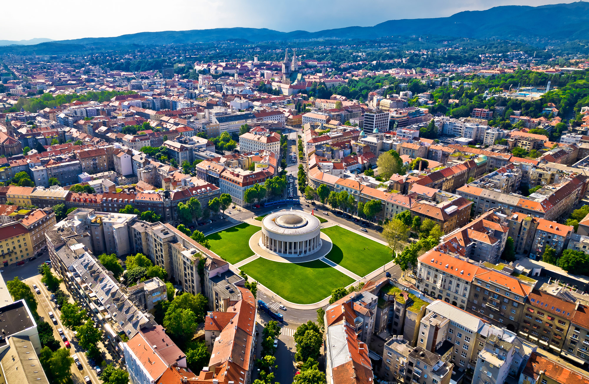 Aerial view of Zagreb, with the circular Meštrović Pavilion in the foreground and hills beyond the city.