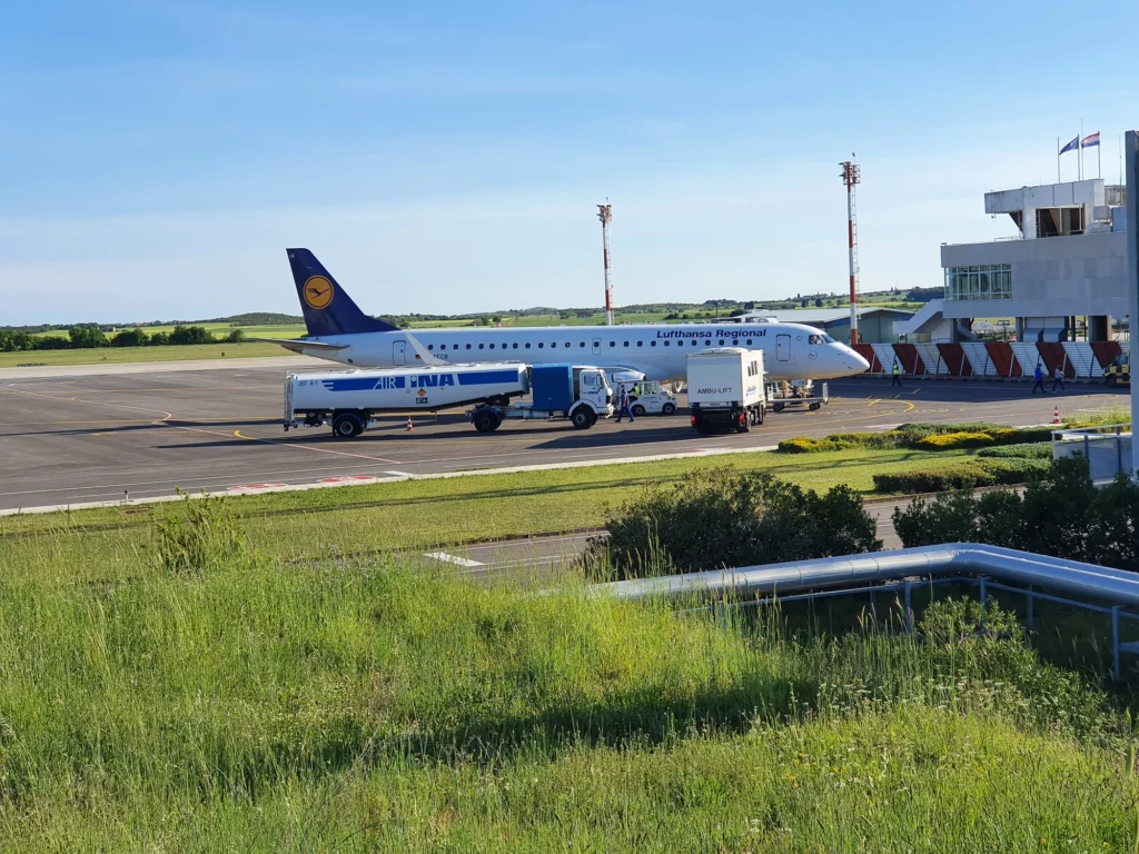 A Lufthansa Regional passenger plane parked beside airport service vehicles in Croatia.