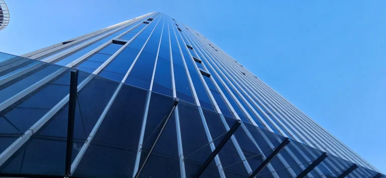 Low-angle view of a modern glass office building against a clear blue sky in Croatia