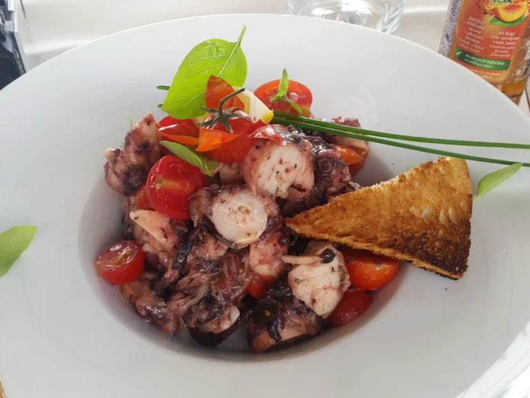 Octopus salad with cherry tomatoes, fresh herbs and toasted bread in Croatia