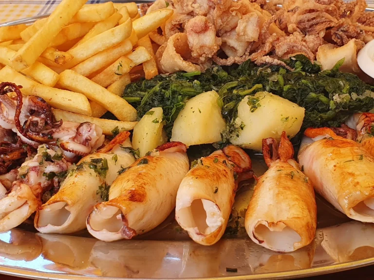 A Croatian seafood platter with fried calamari, golden fries, potatoes and greens