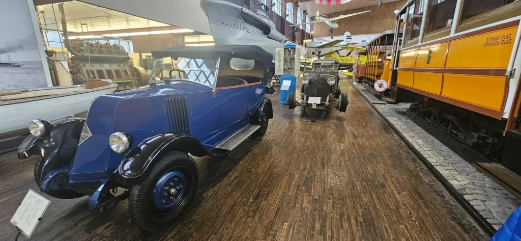 A vintage blue car, yellow tram, aircraft and boats displayed inside a transport museum in Croatia