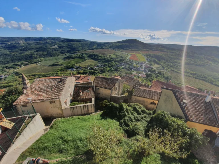 Stone-roofed village houses overlook vineyards and wooded hills in inland Croatia.