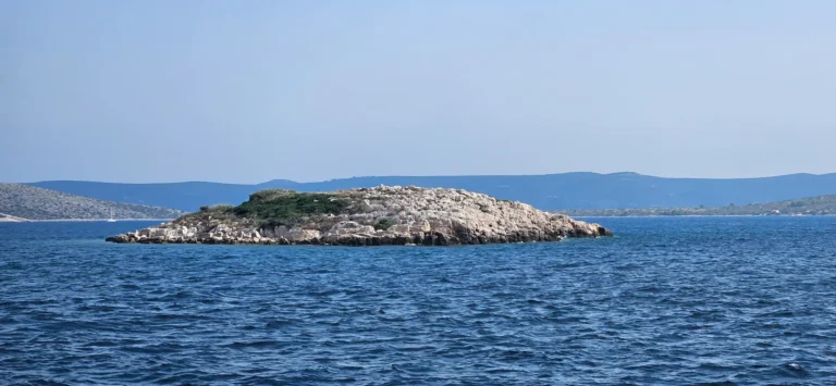 A low rocky islet surrounded by deep blue sea on the Croatian coast.