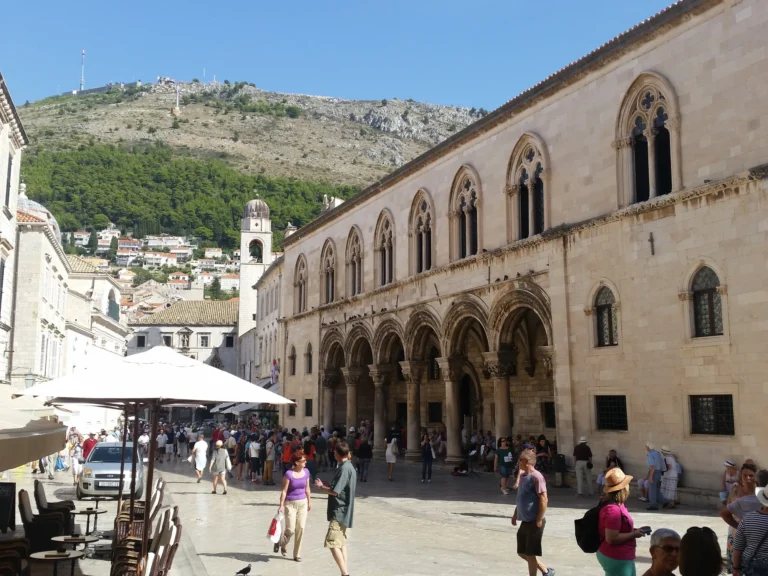 Visitors in the square beside Dubrovnik's Rector's Palace and its arcaded stone façade.