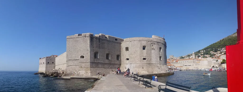 St John Fortress beside Dubrovnik's Old Harbour, with boats and the hillside old town beyond.