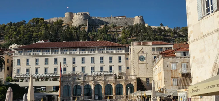 Hvar Town’s hilltop Fortica fortress rises above stone buildings and a clock tower in the old town.
