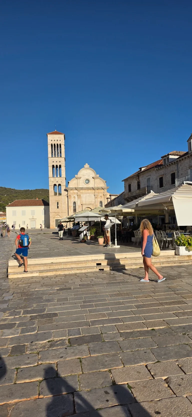 St Stephen's Cathedral and its bell tower overlook the sunlit main square in Hvar Town.