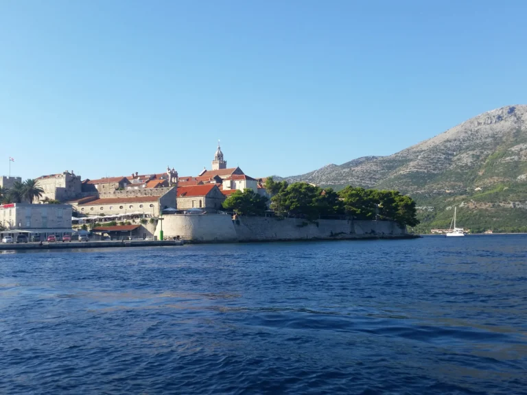 Korčula's stone-walled old town and red-roofed buildings rise above the blue water.