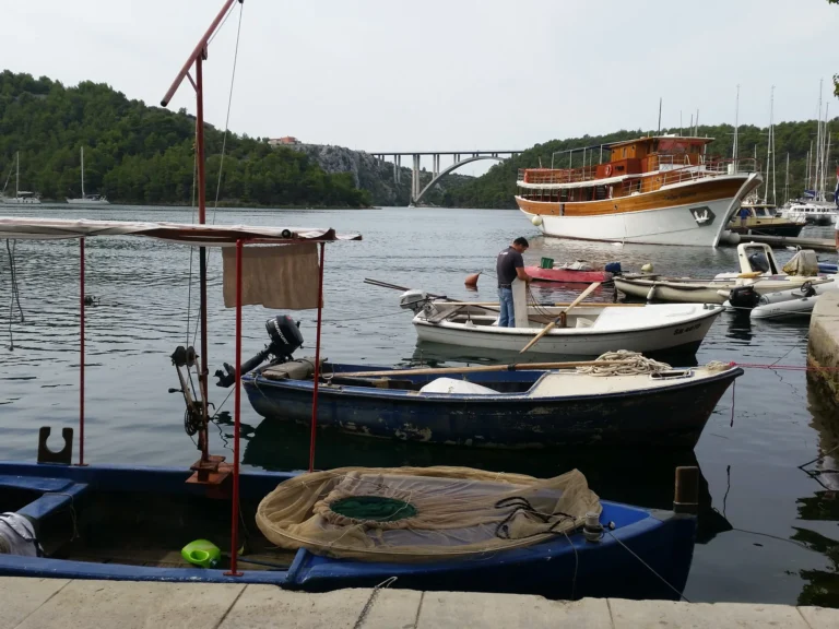 Small boats moored on Lim Bay beneath an arched bridge, with wooded hills along the water.