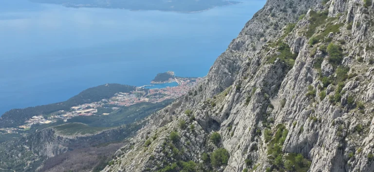 Makarska and the blue Adriatic seen from a steep, rocky mountainside on Biokovo.
