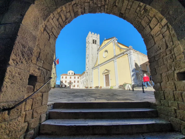 Motovun’s Church of St Stephen and bell tower seen through a stone archway