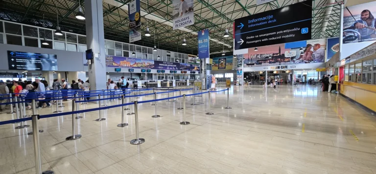 Check-in queues and departure information inside Pula Airport's bright terminal hall.