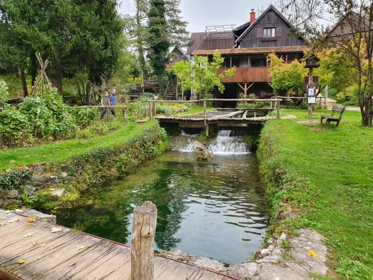 Wooden buildings and footbridges beside a small waterfall and clear stream in Rastoke, Slunj