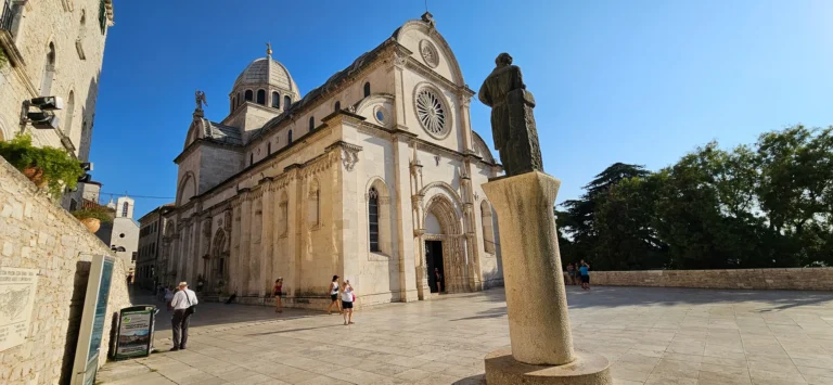 Cathedral of St James in Šibenik, with a stone statue in the sunny forecourt