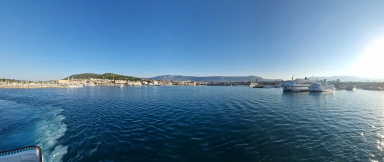 Ferries and waterfront buildings line Split harbour, with dark blue water and mountains beyond.