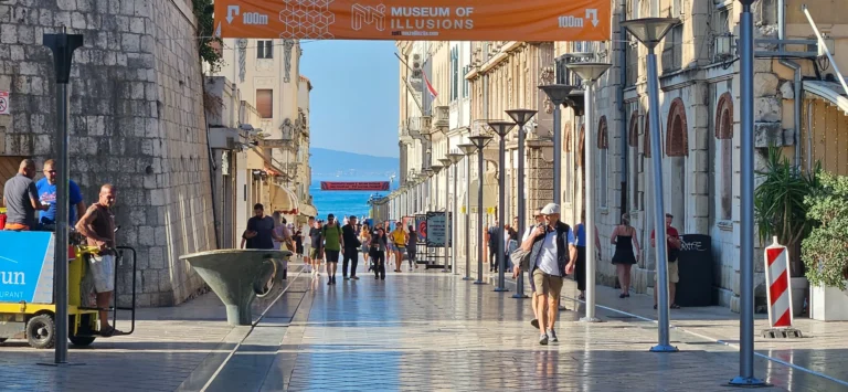 Pedestrians walk along a stone street in Split's old town toward the sea.