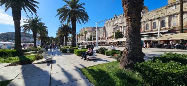 Palm-lined promenade beside cafés and historic buildings on Split's Riva waterfront.