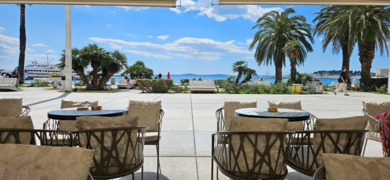 Outdoor café seating faces the palm-lined waterfront and harbour in Split.