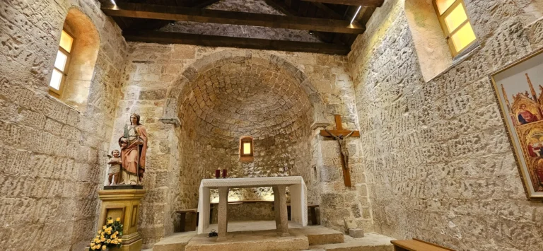 Stone chapel interior with a small altar, a crucifix and religious statues