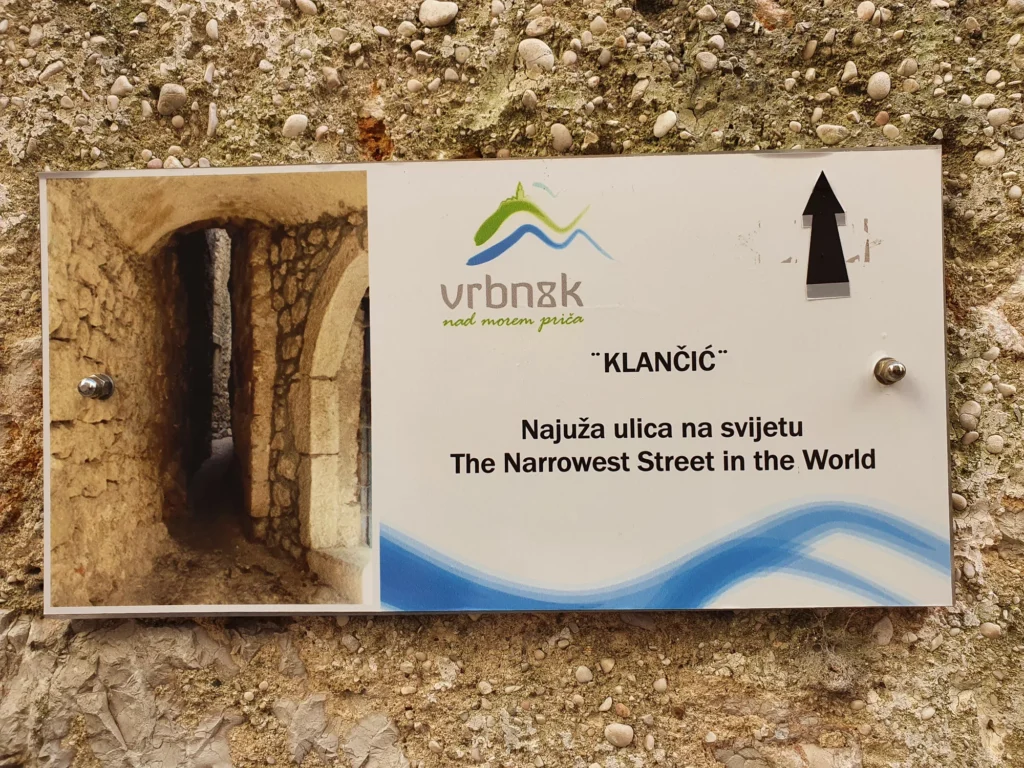 A sign in Vrbnik marks Klančić as the narrowest street in the world and shows a photo of the stone passage.