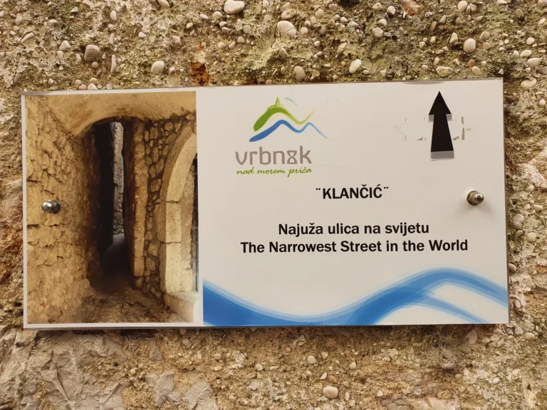A sign in Vrbnik marks Klančić as the narrowest street in the world and shows a photo of the stone passage.